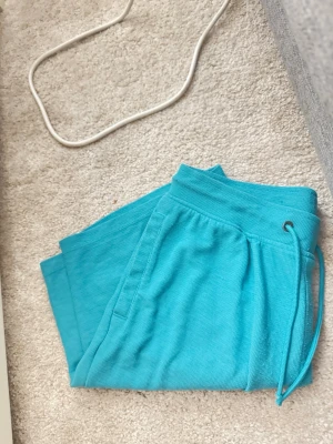 Turkosa mjukisbyxor från Livergy - Snygga turkosa mjukisbyxor från Livergy med dragsko i midjan och sidofickor. Tillverkade i ett mjukt och bekvämt material som passar perfekt för chill dagar hemma eller när du vill ha en avslappnad stil.