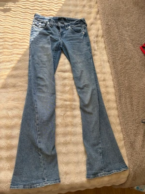True religion jeans  - Jeans från True Religion i mkt bra skick med strassdetaljer på baksidan. Jeansen har ett pytte hål på ena jeansbenet längst ner, det syns på bild. Inget märkvärdigt. Köpte för 1400kr, säljer för 900. Storlek 24.