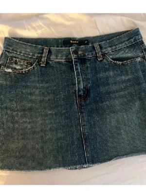 Blå jeanskjol från Crocker - Säljer en klassisk blå jeanskjol från Crocker i kort modell. Kjolen har fem fickor, bälteshällor och rå kant nedtill för en avslappnad look. Perfekt till sommaren och enkel att matcha med olika toppar. Så himla snygg!!