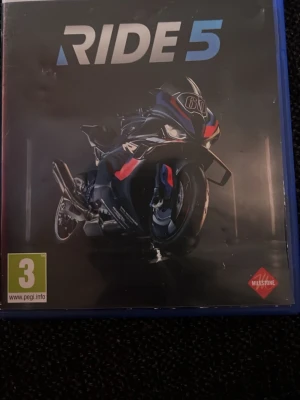 RIDE 5 PS5 spel - Säljer spelet RIDE 5 till PlayStation 5. Omslaget har en sportig motorcykel i svart med blå och röda detaljer. Perfekt för dig som gillar racing och motorcyklar. PEGI 3. Utvecklat av Milestone.