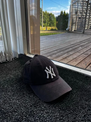 New era keps - Säljer en svart New York Yankees keps med böjd skärm och justerbart spänne bak. Klassisk broderad NY-logga i vitt framtill. Perfekt för dig som vill ha en stilren och sportig look. Kepsen är i bomull och passar till de flesta outfits. Skick 9/10. Pris går att diskutera✅