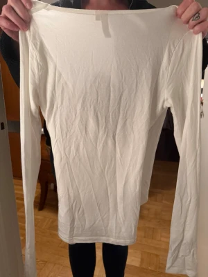 Vit tröja  - Säljer en stilren vit omlottopp med lång ärm. Toppen har en djup v-ringning framtill och är tillverkad i ett mjukt, stretchigt material som känns väldigt skönt den är helt ny från Nelly men den kommer inte till användning 