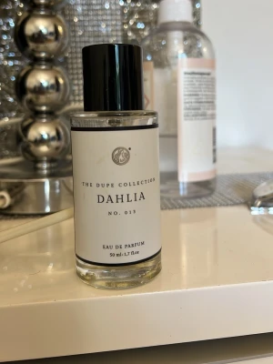Dahlia Curiosa Eau de Parfum 50 ml - Dahlia No. 013 från  Curiosa är en elegant parfym i en stilren, genomskinlig glasflaska med svart lock. Flaskan rymmer 50 ml och har en minimalistisk vit etikett med svart text. Perfekt för dig som gillar exklusiva dofter. Knappt använd, dene blommig