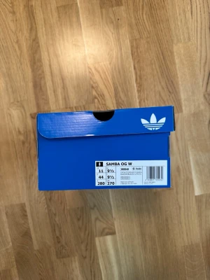 Adidas Samba OG W sneakers - Klassiska Adidas Samba OG W sneakers i originalkartong. Skorna har den ikoniska blåa Adidas-lådan och modellen är känd för sin retrostil med låg profil och tidlös design. Perfekta för dig som gillar streetwear och sportig look.