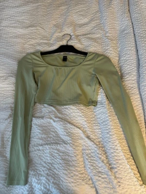 Ljusgrön ribbad croppad topp Shein - Trendig ljusgrön croppad topp från Shein med lång ärm och ribbad struktur. Toppen har en rundad urringning och är perfekt för dig som gillar en enkel men snygg stil. Passar till både jeans och kjol.