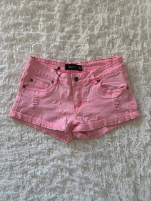 Rosa lågmidjade jeansshorts - Superfina och färgglada rosa shorts i denimliknande material från märket Madonna. Shortsen har snygga slitna detaljer fram, uppvikta benslut och kontrasterande sömmar i en starkare rosa nyans. Klassisk 5-fickorsmodell som är jättesnygg till sommaren! Storlek M på lappen, midjemåttet är ungefär 36cm rakt över så jag skulle säga att det är mer som ett S (alla mått finns i bilderna). ⭐️