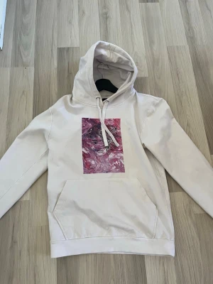 Vit hoodie  - Vit hoodie från The cool elephant med ett rosa/lila tryck. Har använd den 1-2 gånger, har lite små fläckar. Annars väldigt fint skick.   Postar mellan 1-3 dagar efter köp.   Hör gärna av dig om du har frågor eller vill ha fler bilder!