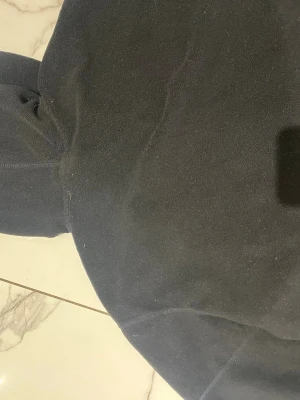 Svart fleecehoodie med dragkedja - Mjuk och enkel svart hoodie i fleece med dragkedja framtill och huva. Perfekt för chill dagar eller när du vill ha något bekvämt och varmt. Klassisk passform och utan synliga loggor eller tryck.