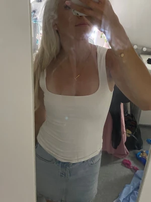Vit linnetopp - Säljer en enkel och stilren vit ribbad tanktop med breda axelband och fyrkantig urringning. Toppen är figurnära och passar perfekt till jeans eller kjol. Materialet ser ut att vara mjukt och stretchigt, troligen bomull eller bomullsblandning.