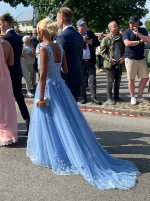 Ljusblå balklänning  - En drömmig ljusblå långklänning med vackra spetsdetaljer och broderade blommor. Klänningen har breda axelband, markerad midja och ett svepande, voluminöst kjolparti i tyll. Perfekt för bal eller student. Säljer då jag redan haft min bal, inget trasigt så gott som ny💎
