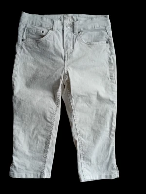 Vita knälånga jeans i strl 34 - Snygga vita jeans med croppad längd och klassisk femficksdesign. Byxorna har raka ben och är tillverkade i ett mjukt bomullsmaterial som känns bekvämt hela dagen. Perfekta för en fräsch och stilren look. Finns i rök- och djurfritt hem. 