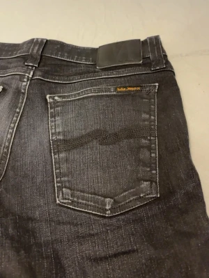 Nudie Jeans - Nudie jeans i svart denim. Buksen er veldig lite brukt. Nypris for denne buksen er 1,5k, men selger her for kun 999kr. Tar også trades for denne buksen i en større størrelse. W31 L34