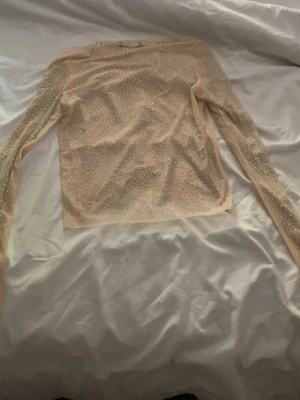 Beige topp från Gina Tricot - Säljer en beige långarmad tröja från Gina Tricot, den är lite genomskinlig nästan som en fest tröja, använd några gånger och är i bra skick💕