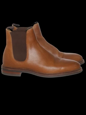 Bruna Chelsea boots Meermin (44,5) - Snygga Chelsea boots i brunt läder med elastiska paneler på sidorna och klassisk siluett. Skorna har en låg klack och rundad tå, perfekta för en stilren look. Yttermaterialet är av präglat läder och sulan är robust för extra komfort. Framstår som nya förutom en fläck som behöver putsas till med skokräm. Storlek 44,5. 