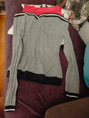 Grå off shoulder tröja från size 14 MAX med ränder 100 proc Bomull - Snygg grå långärmad tröja med off shoulder-design och svarta samt vita ränder vid halsringning, ärmslut och nederkant. Tillverkad i en mjuk mix av bomull och polyester. Perfekt för dig som gillar en sportig men stilren look. Size 14