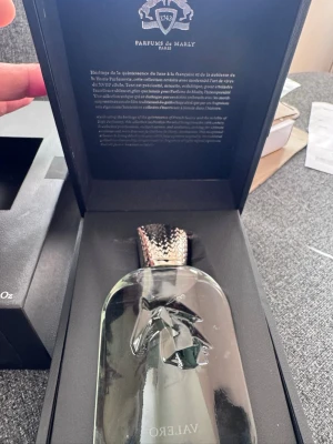 Parfums de Marly Valero parfym - Lyxig parfym från Parfums de Marly i modellen Valero. Flaskan är genomskinlig med elegant relief och har ett exklusivt lock med ormliknande mönster. Kommer i en svart presentförpackning med silverdetaljer och text på insidan av locket.