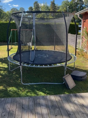 Stor studsmatta med skyddsnät - Säljer en rund studsmatta med svart hoppduk och robust ram i metall. Studsmattan har ett skyddsnät runt om för extra säkerhet och en dragkedja i öppningen. Perfekt för trädgården och för dig som gillar att hoppa och ha kul utomhus.