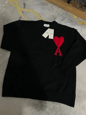 Ami Paris  - Säljer denna fina svarta Ami Paris-tröja med det klassiska röda hjärtat. 🖤❤️ Storlek S.  Tröjan är i fint skick och har en stilren design som passar till nästan allt. Säljer den eftersom jag inte längre använder den och vill göra plats för annat i garderoben.