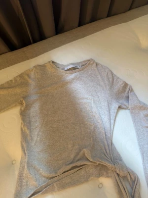 Beige långärmad topp med knyt - Säljer en beige långärmad topp i mjukt material från 157. Toppen har rund halsringning och en snygg knytdetalj i nederkanten. Perfekt att styla med jeans eller kjol för en enkel och clean look.
