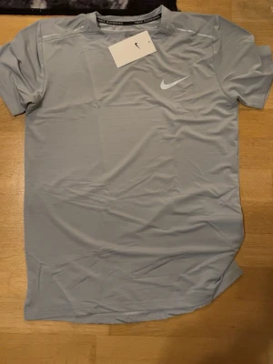 Grått träningsset t-shirt & shorts - Snyggt grått träningsset med t-shirt och matchande shorts. Båda plaggen har en reflekterande logga och är tillverkade i ett lätt, snabbtorkande material som passar perfekt för löpning eller gym. 
