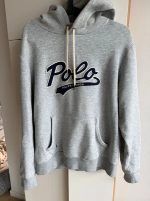 Grå hoodie Polo Ralph Lauren - Snygg grå hoodie från Polo Ralph Lauren i storlek medium. Tillverkad i 66% bomull och 34% återvunnen polyester. Kontakta vid fler frågor eller bilder