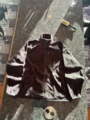 Svart fleecejacka från L.L. Bean - Mysig svart fleecejacka från L.L. Bean med hög krage och dragkedja framtill. Jackan har en bröstficka med dragkedja och två sidofickor. Perfekt för kyliga dagar och enkel att matcha med olika outfits.