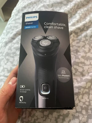 Philips rakapparat 3000X Series - Elektrisk rakapparat från Philips 3000X Series med Skin Protect-teknologi. Svart design med tre roterande rakhuvuden och greppvänligt handtag. Kan användas både vått och torrt, har 45 minuters batteritid och laddas på 1 timme. Perfekt för en bekväm och smidig rakning.
