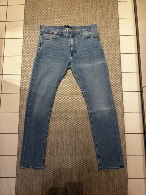 Tommy hilfiger jeans - Snygga ljusblå jeans i slim fit-modell med klassisk. Från Tommy hilfiger är sparsamt använda så i bra skick. Storlek 38/34