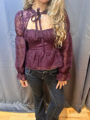Plommonlila blus med puffärmar - Trendig plommonlila blus med transparenta puffiga långärmar i storlek 34, har spets mönster super fin till middagar eller utekvällar, men även skoldagar. Det går att både klä upp och klädd ner, kostade från början 599 kr. Säljer den då den var lite för liten på mig använt ett tillfälle. 