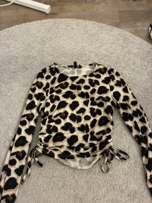 Leopardmönstrad topp från Pieces - Säljer en leopardmönstrad långärmad topp från Pieces. Toppen har snörning i sidorna och är tillverkad i ett tunt, stretchigt material. 