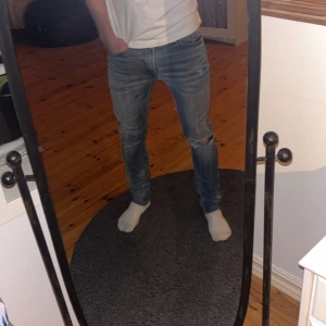 Blå diesel jeans med slitningar  - Snygga diesel jeans i blå tvättad denim. Klassisk femficksdesign, låg midja och slitningar på ena benet som har framkommit efter många års användning. Säljer ett par lika dana i en storlek större också! Hör av dig för minsta lilla fråga 