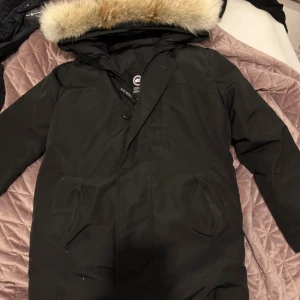 Canada goose chateau red label - Säljer en Svart Canada Goose cheteau med röd label. Köptes förra året i december. Den kommer med päls och är i väldigt gott skick