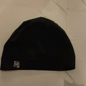 Svart mössa med tryck från decrease - Svart, stilren mössa med ett litet vitt tryck i hörnet från decrease . Enkel och clean design med rundad form, perfekt för dig som gillar minimalistiska accessoarer. Materialet känns mjukt och smidigt, passar bra till streetwear och chill outfits.