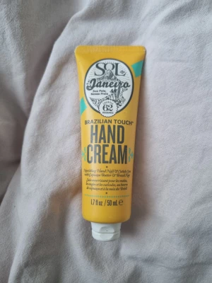 Sol de Janeiro Brazilian Touch Hand Cream - Sol de Janeiro Brazilian Touch Hand Cream i en gul tub på 50 ml. Innehåller Cupuaçu Butter och Brazil Nut, med Cheirosa 62-doft. Tuben är gjord av 33% brasilianskt sockerrörsbaserat material och har en praktisk vit flip-top öppning. Använd