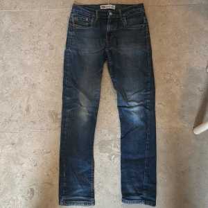 Levi's 512 Slim Taper jeans blå - Säljer ett par Levi's 512 Slim Taper jeans i klassisk blå tvätt. Jeansen har 4 fickor, snygga slitningar och smal passform som smalnar av vid ankeln.