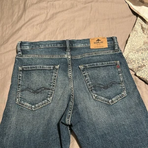 Blå Replay jeans straight fit - Säljer ett par klassiska blå jeans från Replay med snygga slitningar och raka ben. Jeansen har fem fickor, tydliga sömmar och Replay-logga på bakfickan. Passar dig som gillar en tidlös och chill stil. Köpte dom för 1100kr nya. 