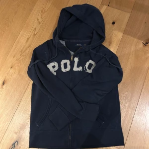 Marinblå hoodie från Polo Ralph Lauren - Snygg marinblå hoodie från Polo Ralph Lauren med stor vit POLO-applikation på bröstet. 