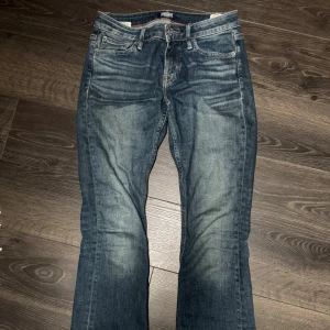 Crocker blå bootcut jeans - Säljer ett par klassiska Crocker jeans blå med snyggt slitna detaljer. Modellen är bootcut 231 slim och har fem fickor, samt läderpatch bak. Jeansen är tillverkade i robust denim och har en autentisk vintagekänsla. Midjemått 36, 19 från gren till midja, 78 innerbenslängd, 22 benöppning