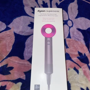Dyson Supersonic - Dyson Supersonic hårfön med fem stylingtillbehör: stylingkoncentrator, smoothing nozzle, diffuser, gentle air och flyaway attachment. Snabb torkning utan extrem värme, passar olika hårtyper. Produkten ser ut att vara i mycket gott skick, inga synliga defekter eller slitage.