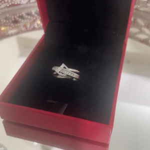 Silverring med glittrande stenar från Dior  - Snygg silverfärgad ring med glittrande stenar i ett korsat mönster. Ringen har en modern design med infattade små stenar som ger extra bling. Perfekt för dig som vill sticka ut med en elegant detalj på handen. Boxen saknas!!!!!!!