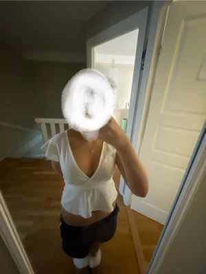 Vit omlottopp med volangärm - Säljer en söt vit omlottopp med djup v-ringning och volangärmar. Toppen har knyt i midjan och en lätt utsvängd nederdel som ger en feminin siluett. Perfekt för dig som gillar en romantisk och fräsch stil.