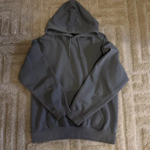 Grå hoodie från H&M Relaxed Fit - Säljer en grå hoodie från H&M i relaxed fit. Tröjan har huva med snörning, magficka och långa ärmar med ribbade muddar. Perfekt för chill dagar och enkel att matcha med jeans eller joggers. Har färgen turkosblå