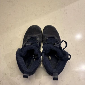 Nike Air mörkblå mocka - Nike Air  mörkblå mocka med matchande snörning och platt sula. Insidan är fodrad med mjukt material för extra komfort. Klassisk Swoosh-logga på sidan och robust yttersula med cirkulärt mönster. Perfekt för dig som gillar streetwear och snygg design.