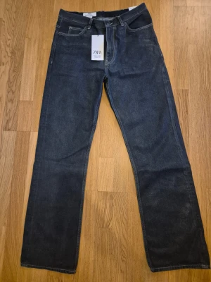 Mörkblå straight jeans från Zara - Mörkblå jeans från Zara Rivoli Paris Winter '23 med klassisk femficksdesign och raka ben. Jeansen har normal passform och är tillverkade i robust denim. Perfekta för dig som gillar en clean och tidlös look. Aldrig använd, Pristaggen kvar. Köpt I Köpenhamn.   Size US32 
