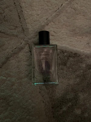 Dark Mirage Eau de Parfum - Minimalistisk parfymflaska med modern design. Texten på flaskan visar 'Eau de Parfum' och 'Dark Mirage'. Perfekt för dig som gillar stilrena detaljer och vill sticka ut med något unikt lite använd.