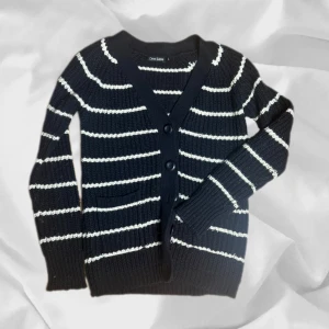 Randig Stickad Kofta - Snygg cardigan i storlek L men sitter som S/XS, – enkel att matcha och skön att bära. Ett stilrent val, noggrant utvalt med omsorg av AM Clothing.  📩 Frågor? Hör gärna av dig! 📲 Följ oss här på Plick för fler uppdateringar. ♻️ Tack för att du handlar mer hållbart med AM Clothing!