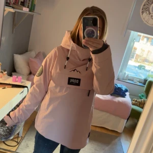 Dope snowboard jacka, soft pink - Säljer en ljusrosa vindjacka från Dope med stor huva och coolt bergstryck på bröstet. Jackan har snörning i huvan, stor ficka med dragkedja framtill och patch på ärmen. Används som jacka om du vill åka skidor/snowboard. Använd 1 gång i sälen!