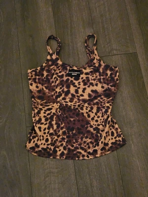 Leopardmönstrad linnetopp Dolce & Gabbana - Säljer en snygg leopardmönstrad linnetopp från Dolce & Gabbana x Skims. Toppen är ribbad med smala axelband och har en beige och mörkbrun färgkombination. Tillverkad i Italien, perfekt för dig som gillar statement-plagg och djurmönster. Toppen är aldrig avnänt och är i limited edition🎀💕 #limited #y2k #d&g 