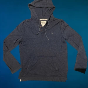 Mörkblå hoodie Abercrombie & Fitch - Snygg mörkblå hoodie från Abercrombie & Fitch med huva och knappar vid halsen. Bara höra av dig vid funderingar😁