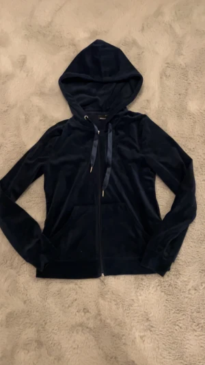 Mörkblå velour hoodie med dragkedja - Snygg mörkblå hoodie från Gina tricot i mjuk velour med huva och snörning. Tröjan har långa ärmar, praktisk ficka framtill och dragkedja hela vägen. Perfekt för chill dagar och när du vill vara extra comfy.